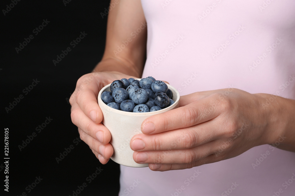 Woman holding crockery with juicy fresh blueberries in hands, closeup view Woman holding crockery with juicy fresh blueberries in hands, closeup view
