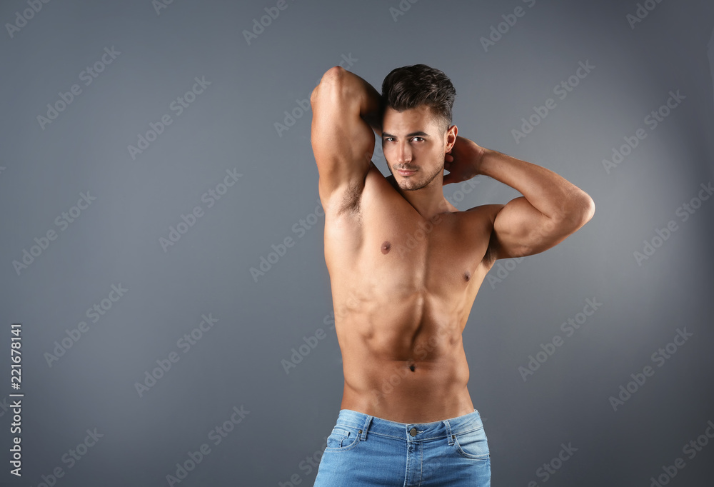 Shirtless young man in stylish jeans on grey background