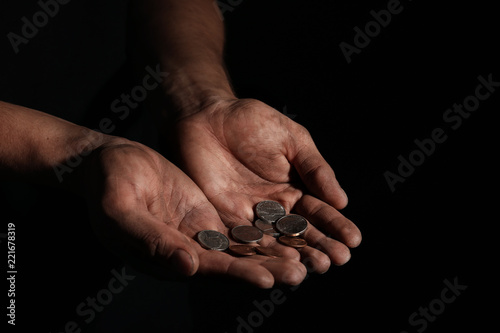 Poor man with coins on dark background, closeup