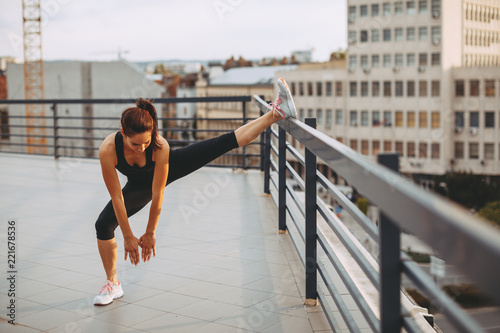 Young woman stretching legs on the roof of the building