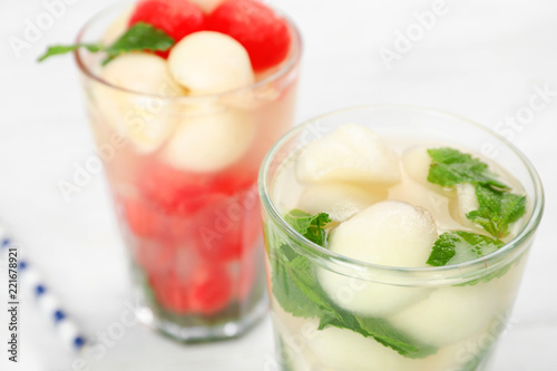 Glass with tasty melon ball drink on table, closeup