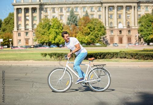 Handsome young hipster man riding bicycle outdoors