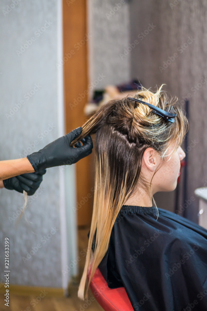 Naklejka premium The hairdresser applies nutritious and healing components to damaged hair, applying botox to the hair, combs every strand