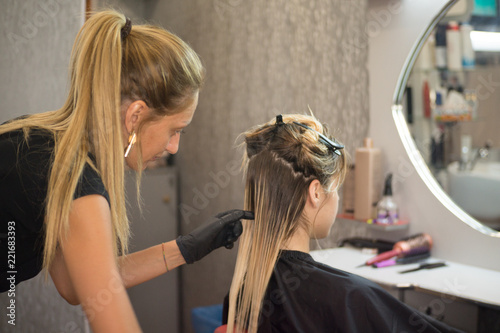 The hairdresser applies nutritious and healing components to damaged hair, applying botox to the hair, combs every strand