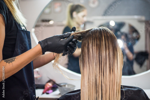 The hairdresser applies nutritious and healing components to damaged hair, applying botox to the hair, combs every strand