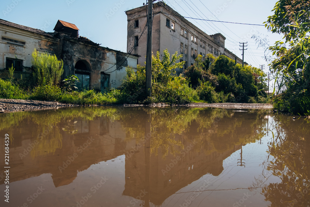 Abandoned buildings reflected in pool of rainwater