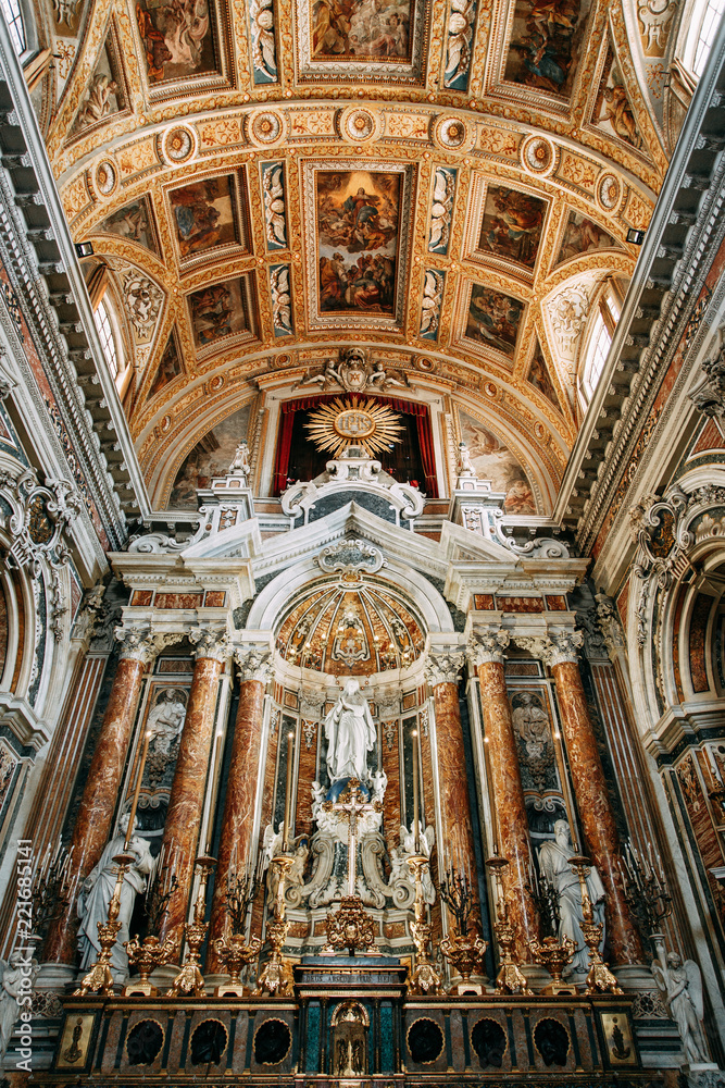 Church in Naples, frescoes and stucco work inside. Beautiful decoration and historical vaults. Symmetry and paintings under the dome. The organ is gilded, the altar, and the icons on the walls.