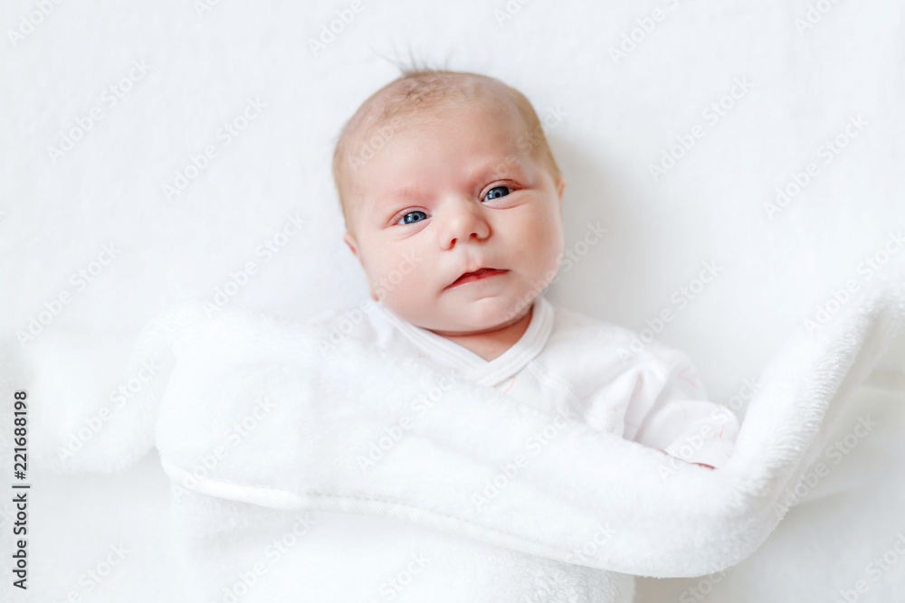 Cute adorable newborn baby in white bed and wrapped in blanket. New born child, little girl looking surprised at the camera. Family, new life, childhood, beginning concept Cute adorable newborn baby in white bed and wrapped in blanket. New born child, little girl looking surprised at the camera. Family, new life, childhood, beginning concept