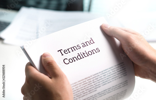 Terms and conditions text in legal agreement or document about service, insurance or loan policy. Lawyer or client holding contract paper in office. photo