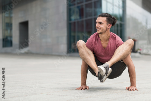 Happy man doing advanced yoga asana on the street