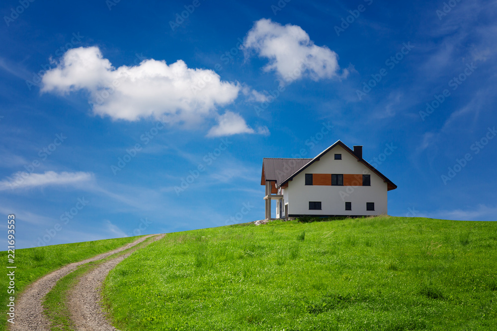 New built modern house on the green hill, under beautiful blue sky New built modern house on the green hill, under beautiful blue sky