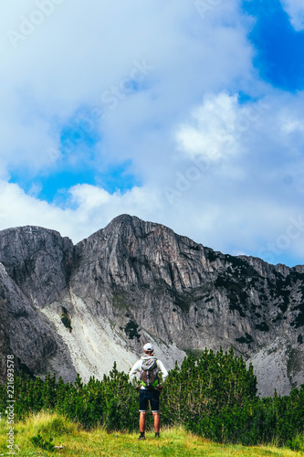 Fototapeta Naklejka Na Ścianę i Meble -  Beautiful alpine high mountains landscape, hiking young man. One male backpack tourist watching amazing green hills.