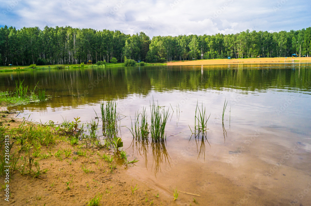 Natural forest lake with artificial sandy beach for free public leisure activities. Moscow residential suburb, Zarya district, Balashikha. Russia.