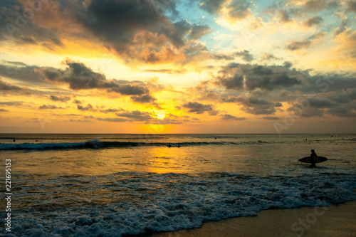 a surfer entering the ocean at sunset