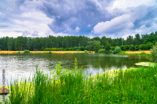 Natural forest lake with artificial sandy beach for free public leisure activities. Moscow residential suburb, Zarya district, Balashikha. Russia.