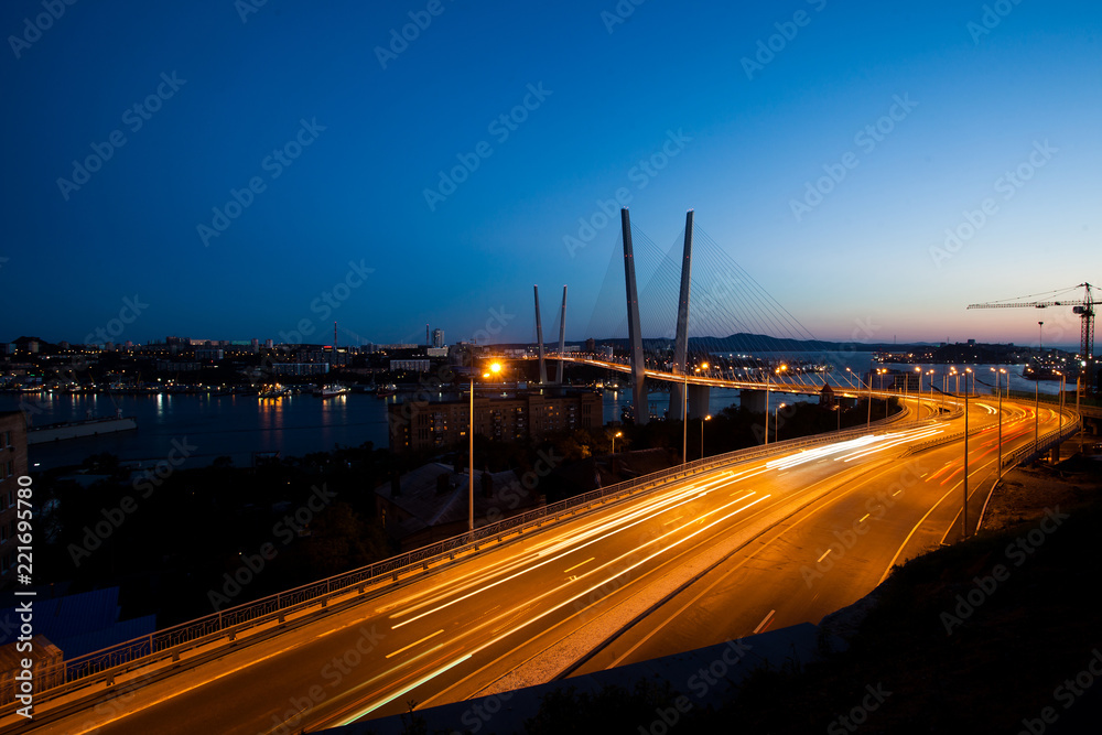 Golden cable-stayed bridge road car traffic from above. Modern Vladivostok Russia night illumination. Old and modern central buildings.	
