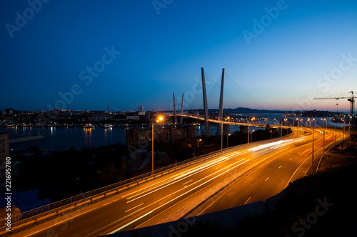 Golden cable-stayed bridge road car traffic from above. Modern Vladivostok Russia night illumination. Old and modern central buildings.	