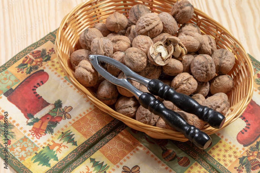 Fototapeta premium Nutcracker on top of some walnuts and a cracked walnut on a table cloth on a wooden table