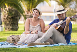 romantic couple man and woman senior adult playing guitar in a serenade for love and relationship. outdoor together leisure friendship activity for cheerful beautiful people enjoying the day and sun