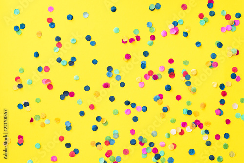 Flatlay of bright yellow background with colourful paper confetti