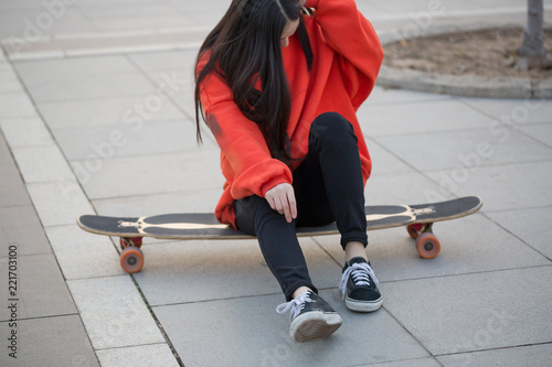 Young woman sitting on her skateboard