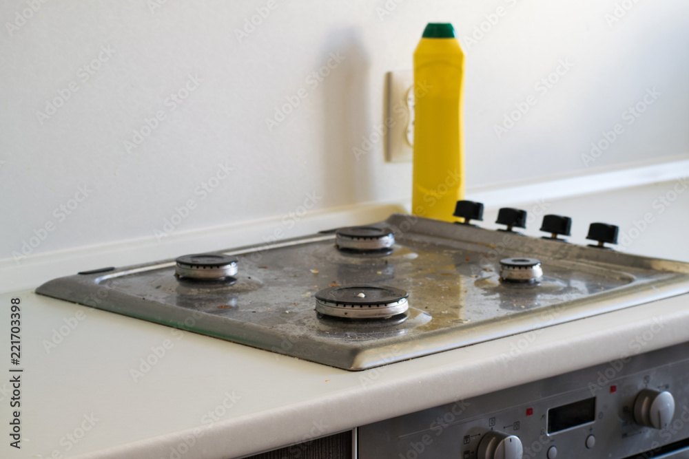 The cleaning of the kitchen. Very dirty gas stove. Cleaning the gas stove with a cleaning agent. The cleaning of the kitchen. Very dirty gas stove. Cleaning the gas stove with a cleaning agent.
