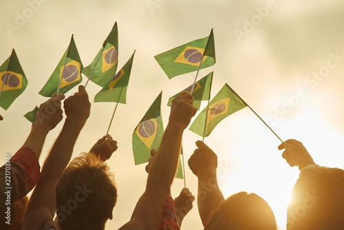 Hands holding brazil flags. Together - we are force, brazilian patriots. Eveining sunny background. photo