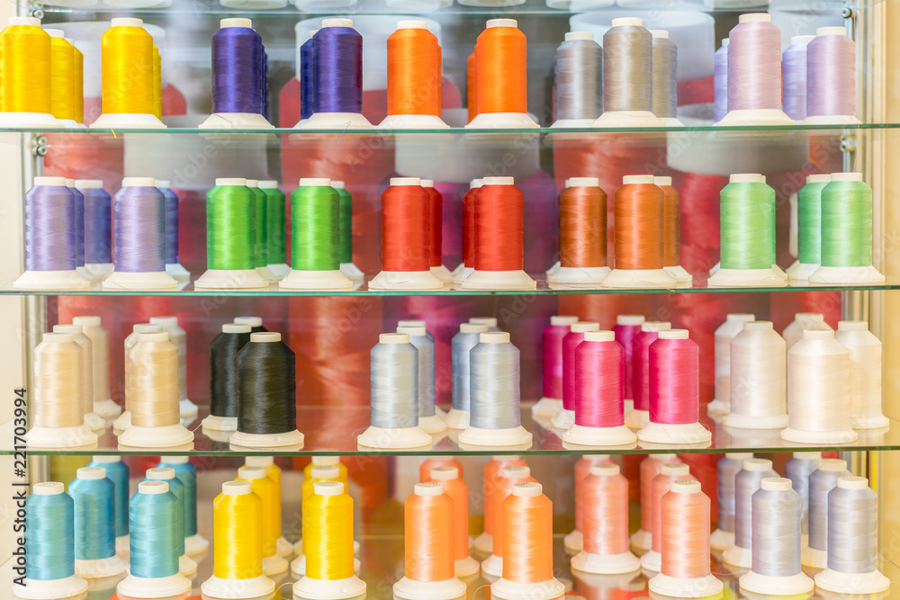Colorful embroidery thread spool using in garment industry, row of multicolored yarn rolls, sewing material selling in the market. Top view of sewing threads pushed all together like tiles Colorful embroidery thread spool using in garment industry, row of multicolored yarn rolls, sewing material selling in the market. Top view of sewing threads pushed all together like tiles