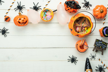 Table top view aerial image of decoration Happy Halloween day background concept.Flat lay accessories essential object to party the pumpkin & sweet candy on white wooden.Space for creative design.
