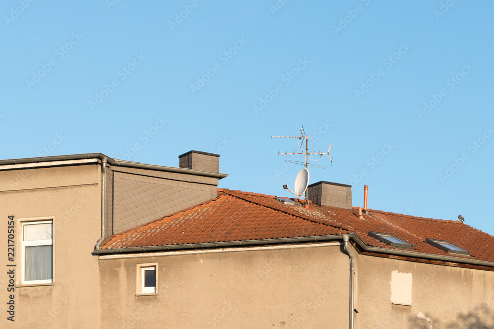 tv antenna and satellite dish on an old house roof