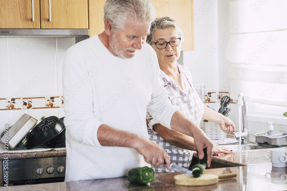 senior adult caucasian couple at home preparing dinner or lunch together. relationship and family lifestyle for people married in love. real people scene in the kitchen. together relationship forever senior adult caucasian couple at home preparing dinner or lunch together. relationship and family lifestyle for people married in love. real people scene in the kitchen. together relationship forever