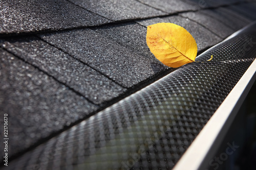 Photo Plastic guard over gutter on a roof with a leaf stuck on the outside