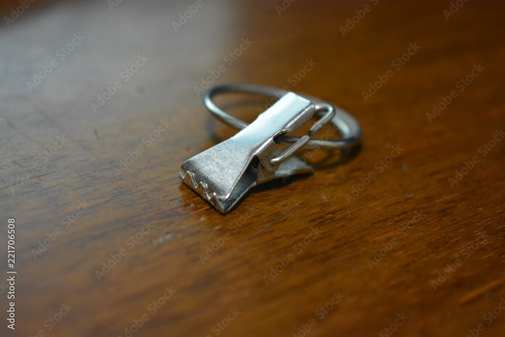 Metal clip of a crocodile with a ring on a brown lacquered wooden background Metal clip of a crocodile with a ring on a brown lacquered wooden background