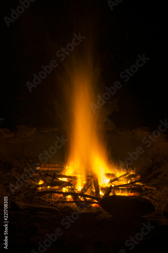 Burning campfire at night. A glowing fire in the darkness. Flying flames from campfire.