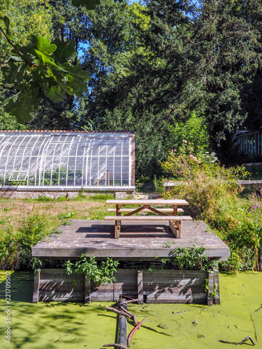 Small picnic area next to an old greenhouse and the river in the center of the Roosendael Abbey public park in Walem, near Mechelen, Belgium photo