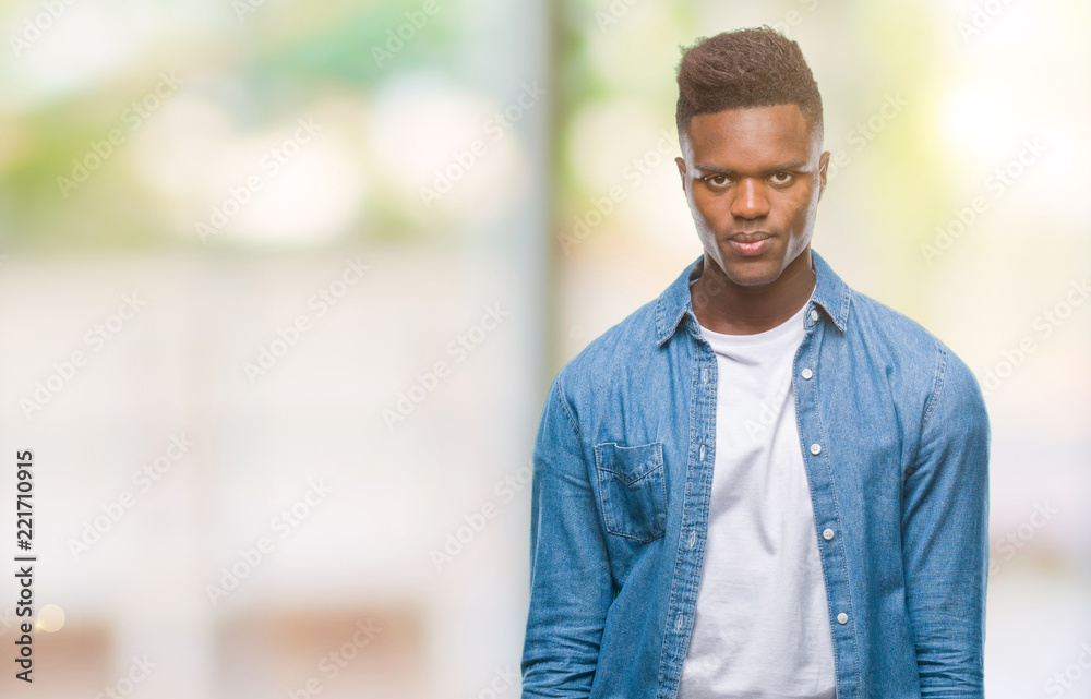 Young african american man over isolated background with serious expression on face. Simple and natural looking at the camera. Young african american man over isolated background with serious expression on face. Simple and natural looking at the camera.