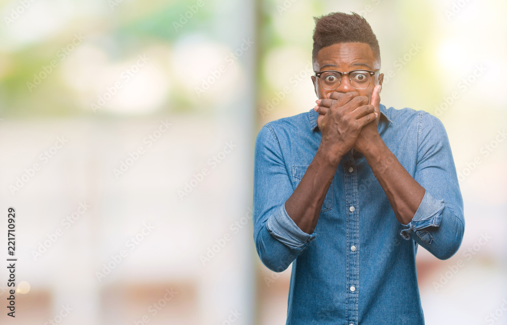 Naklejka premium Young african american man over isolated background shocked covering mouth with hands for mistake. Secret concept.