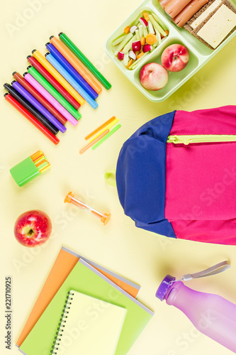 School concept flat lay. Kid backpack, lunchbox, water bottle, notebook, markers on wooden desktop