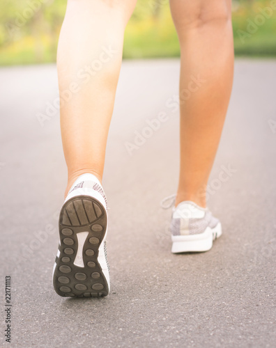 Girl runner feet jogging on street.