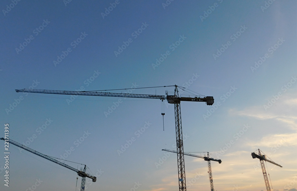 Nice photo of cranes on a construction site against the sky in the light of the setting sun