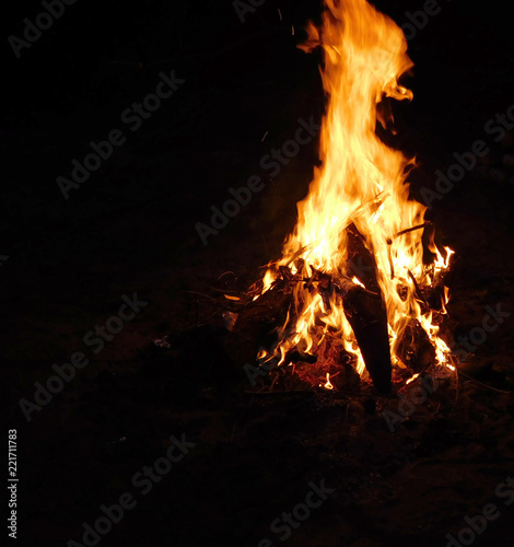 A nice photo of a bonfire at night, wood pieces burning in the field