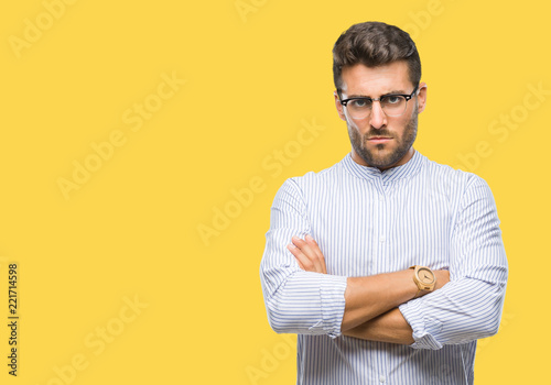 Young handsome man over isolated background skeptic and nervous, disapproving expression on face with crossed arms. Negative person.