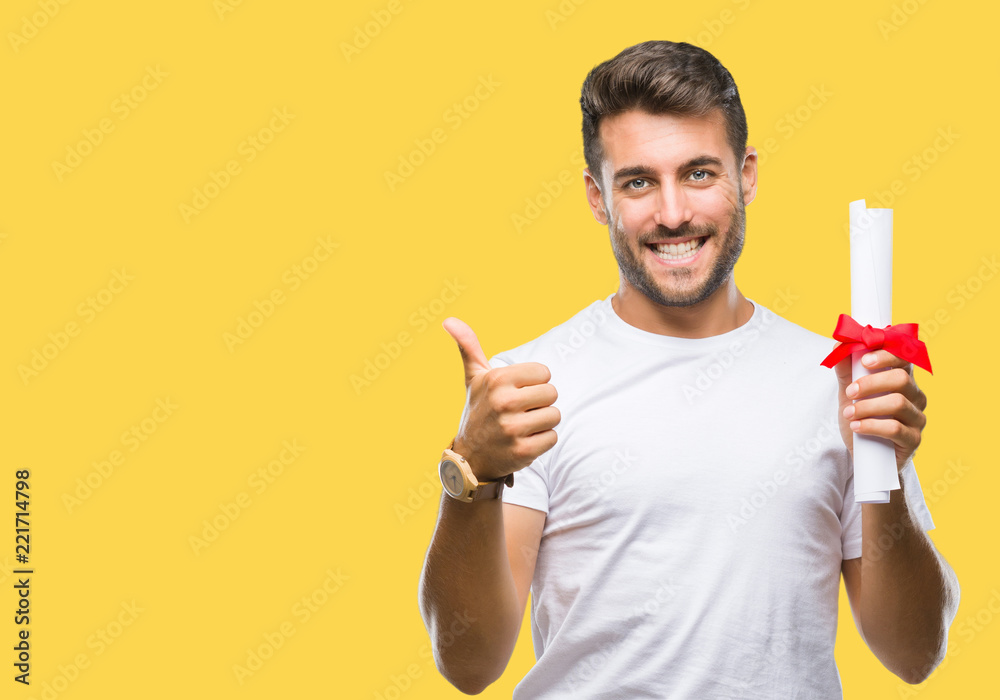 Young handsome man holding degree over isolated background happy with big smile doing ok sign, thumb up with fingers, excellent sign