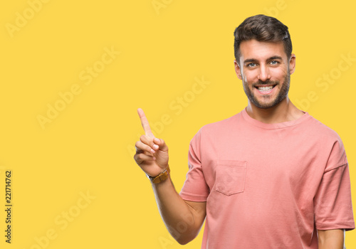 Young handsome man over isolated background with a big smile on face, pointing with hand and finger to the side looking at the camera.
