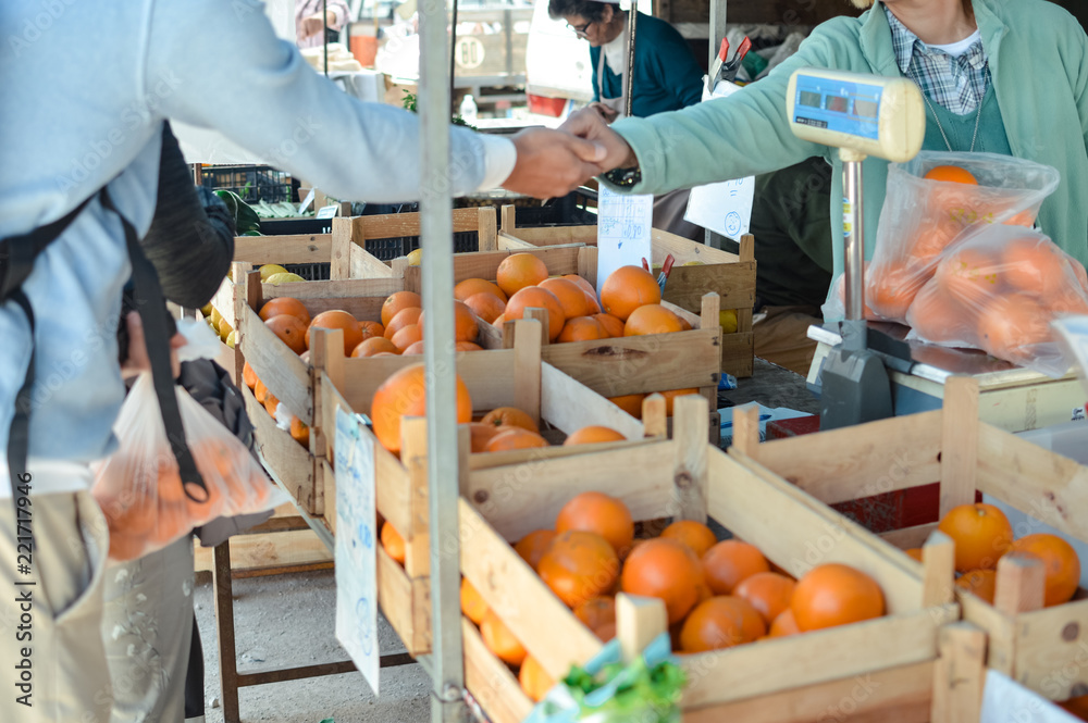 Close up on hand of a person choosing picking up tasty citrus fruits, buying seasonal ingredient fresh natural background. Healthy lifestyle, traditional nutrition local marketplace season choice