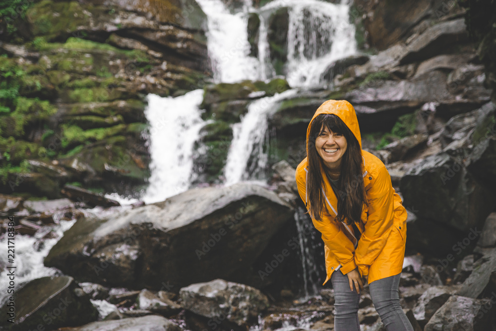 woman standing in yellow raincoat and looking at waterfall woman standing in yellow raincoat and looking at waterfall