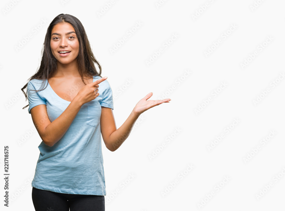 Young beautiful arab woman over isolated background amazed and smiling to the camera while presenting with hand and pointing with finger. Young beautiful arab woman over isolated background amazed and smiling to the camera while presenting with hand and pointing with finger.