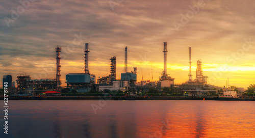 panorama view of petrochemical refinery oil energy plant factory industrial the fuel power storage design on morning skyline with sunshine at golden hour in sky with reflection on water riverside.