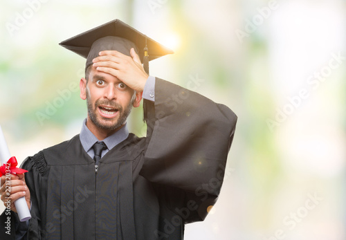 Young handsome graduated man holding degree over isolated background stressed with hand on head, shocked with shame and surprise face, angry and frustrated. Fear and upset for mistake.