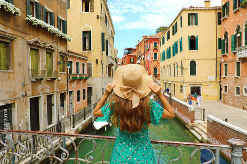 Sweet romantic girl charmed by Venice landscape. Rear view of female tourist on a bridge in Venice, Italy.